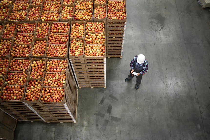 Top view of worker standing by apple fruit crates in organic foo