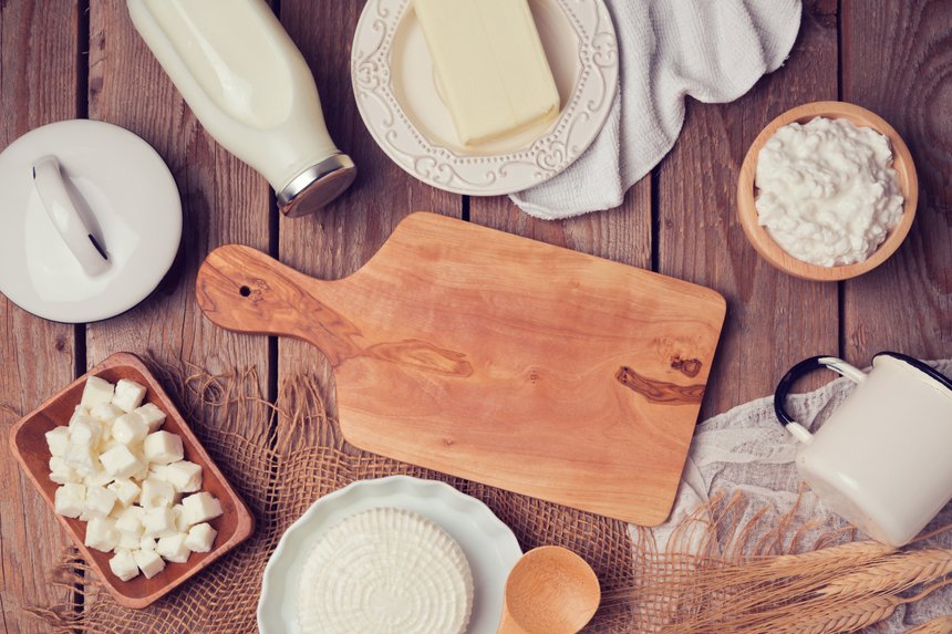 Milk, cheese and butter with cutting board on wooden background. View from above. Flat lay