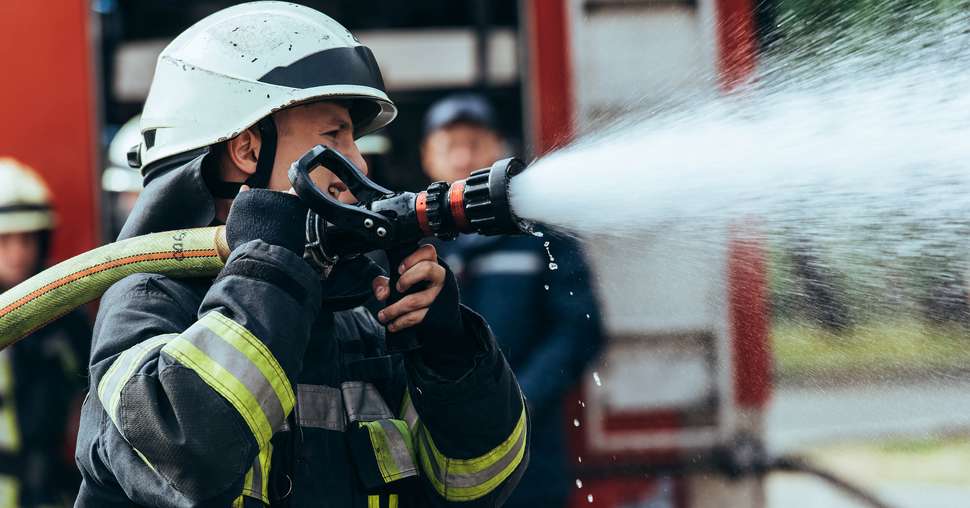 selective focus of firefighter with water hose extinguishing fir