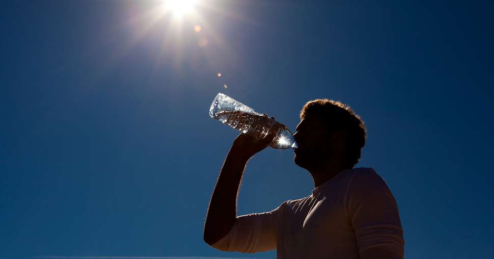 Mann trinkt Wasser aus Flasche unter Sonne