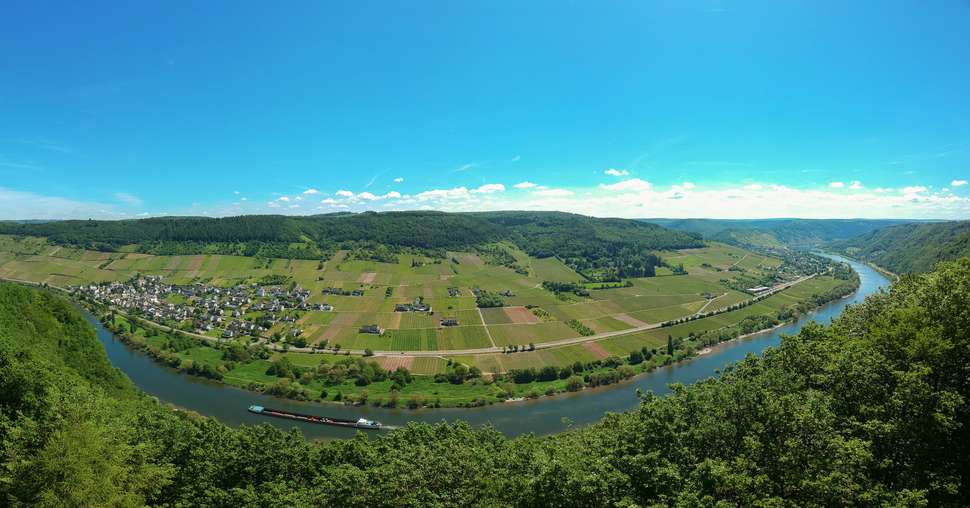 Panoramic, aerial view of the Moselle Valley and the river Moselle with forests en vineyards and the village Burg under a blue sky in the afternoon. Bernkastel-Wittlich, Germany. Copy space included.