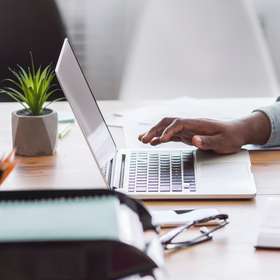 African American worker noting information from laptop in office