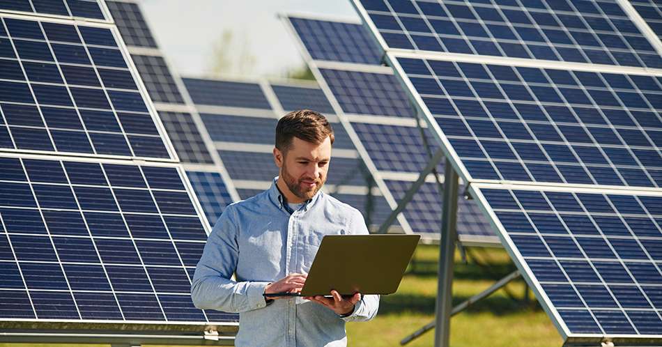 Holding laptop. Engineer with photovoltaic solar panels outdoors