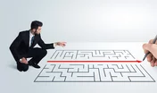 Business man looking at hand drawing solution for maze