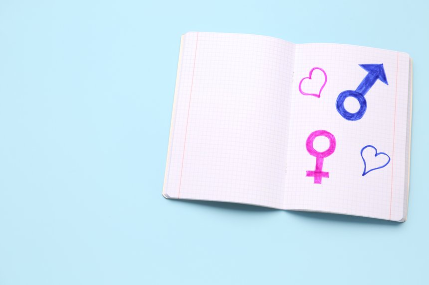 Notebook with drawn symbols of male and female on blue background