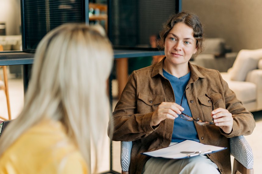 A female psychologist consults a client while sitting in the office and listening and watching carefully.