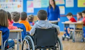 Classroom group children sitting desks teacher standing front Inclusive classrooms with diverse