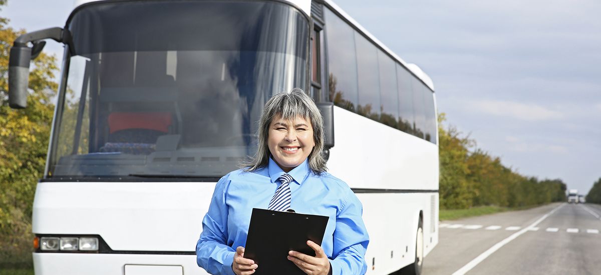 Female driver standing in front of bus